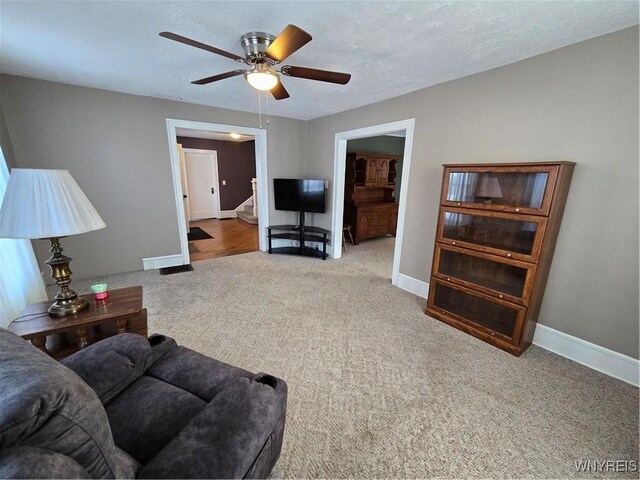 living room with ceiling fan, carpet flooring, and a textured ceiling