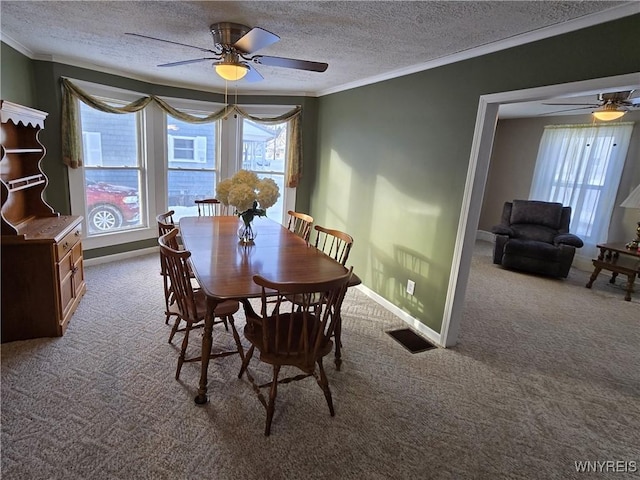 dining room with a textured ceiling, ornamental molding, ceiling fan, and carpet