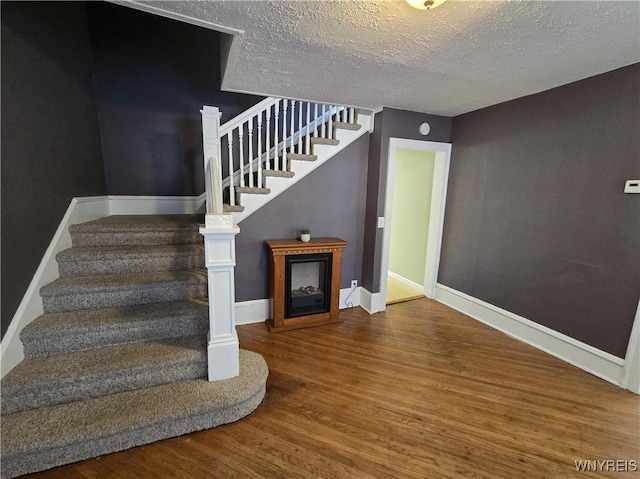 stairs with hardwood / wood-style floors and a textured ceiling