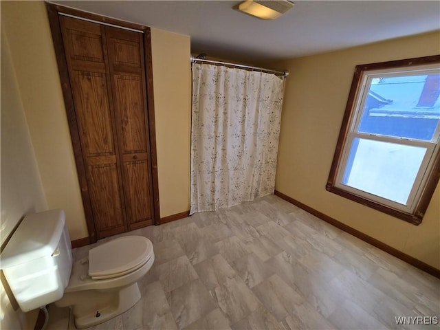 bathroom with curtained shower, a wealth of natural light, and toilet