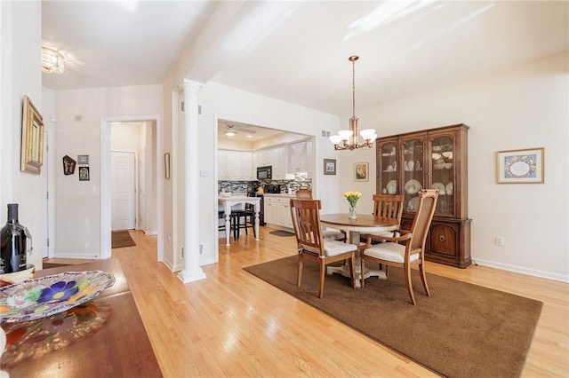 dining room featuring decorative columns, ceiling fan with notable chandelier, and light hardwood / wood-style floors