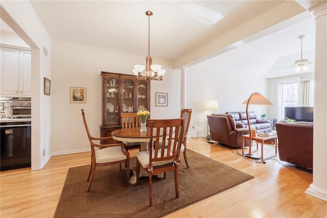 dining space featuring decorative columns, ceiling fan with notable chandelier, and light hardwood / wood-style floors