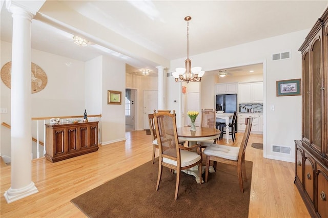 dining area with decorative columns and light hardwood / wood-style flooring