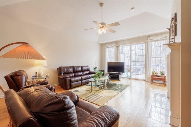 living room with ceiling fan, vaulted ceiling, and light hardwood / wood-style flooring