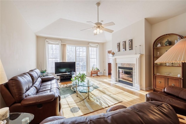 living room featuring a high end fireplace, ceiling fan, and light wood-type flooring