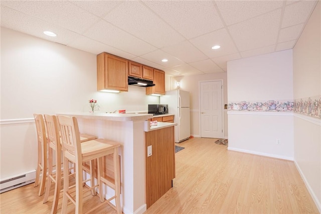 kitchen with a breakfast bar, light hardwood / wood-style flooring, baseboard heating, kitchen peninsula, and white fridge