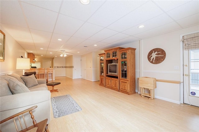 living room featuring a paneled ceiling, ceiling fan, and light wood-type flooring