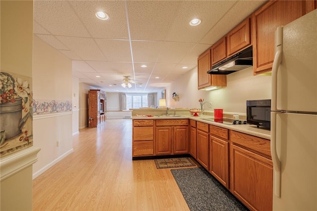 kitchen featuring sink, light wood-type flooring, white refrigerator, kitchen peninsula, and black electric stovetop