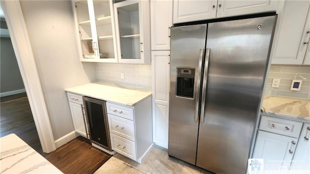 kitchen featuring white cabinetry, stainless steel refrigerator with ice dispenser, light stone counters, wine cooler, and tasteful backsplash