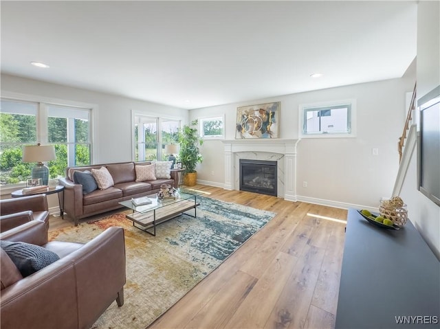 living room with a high end fireplace and light hardwood / wood-style flooring