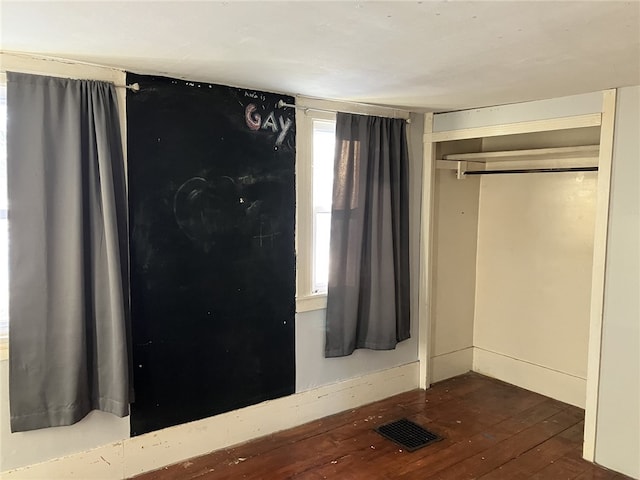 unfurnished bedroom with dark wood-type flooring and a closet