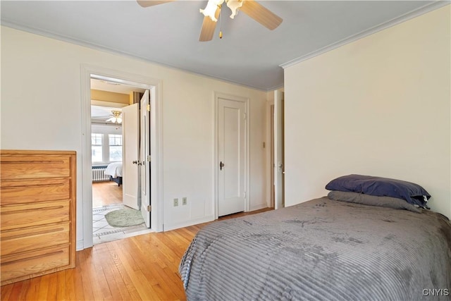 bedroom with crown molding, radiator, ceiling fan, and light wood-type flooring