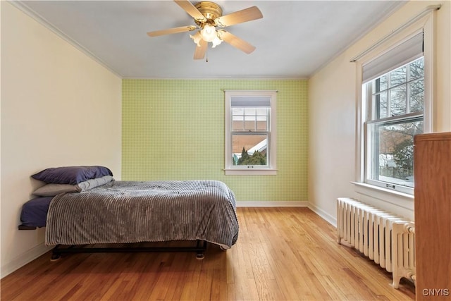 bedroom with crown molding, radiator heating unit, ceiling fan, and light wood-type flooring