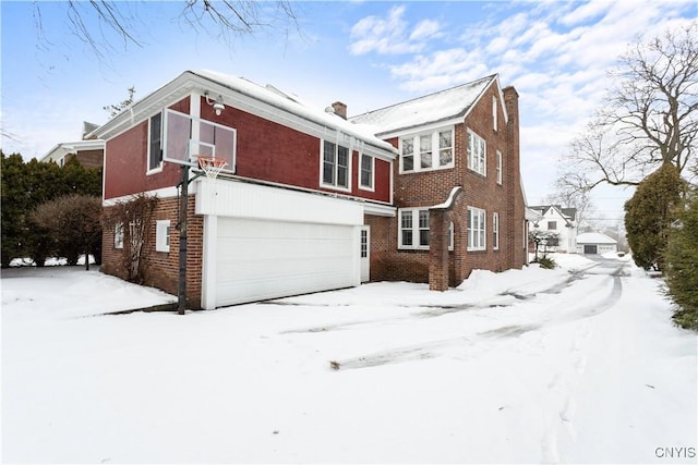 snow covered property with a garage