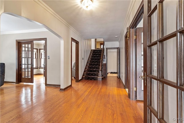 hall with ornamental molding, light wood-type flooring, and french doors