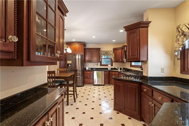 kitchen featuring stainless steel appliances, sink, decorative backsplash, and dark stone counters