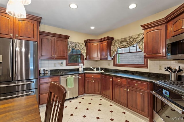 kitchen with appliances with stainless steel finishes, sink, dark stone countertops, and backsplash