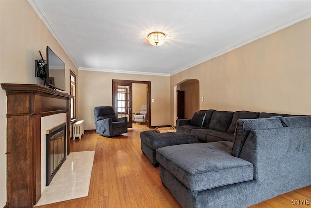 living room with ornamental molding, radiator heating unit, and light hardwood / wood-style floors