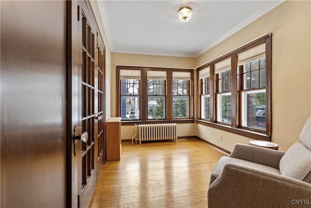 sitting room with ornamental molding, radiator heating unit, and light hardwood / wood-style flooring