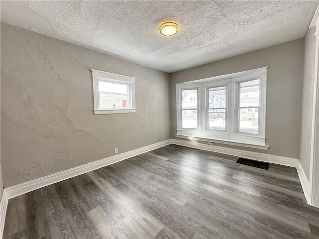 unfurnished room with a textured ceiling and dark hardwood / wood-style flooring