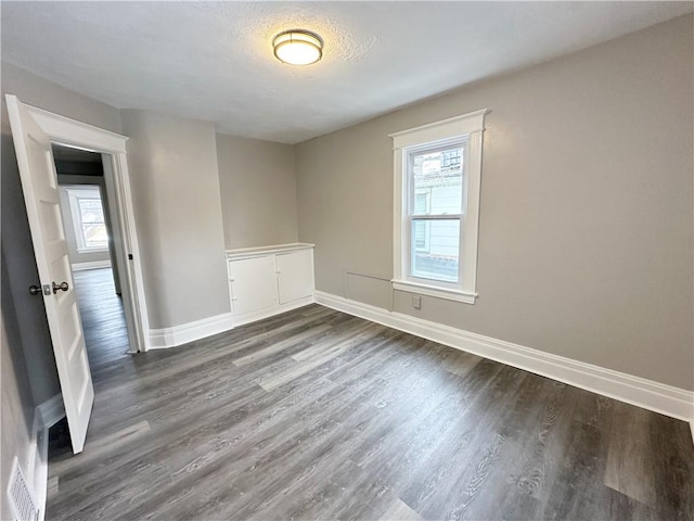 empty room with a textured ceiling and dark hardwood / wood-style flooring