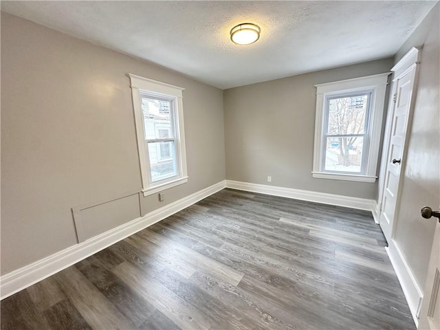 unfurnished room with plenty of natural light, dark hardwood / wood-style floors, and a textured ceiling