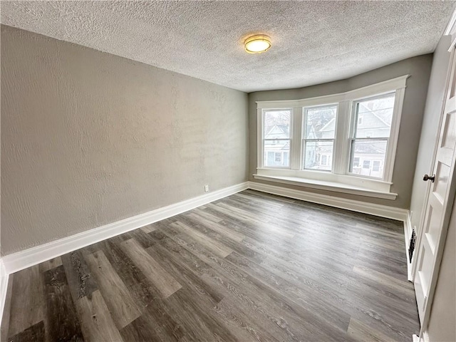 empty room with dark hardwood / wood-style floors and a textured ceiling