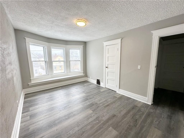 unfurnished room with dark wood-type flooring and a textured ceiling