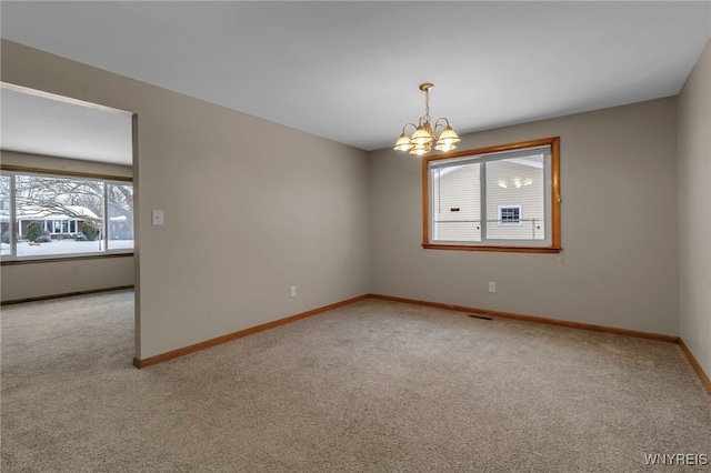 carpeted empty room with a notable chandelier