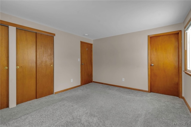 unfurnished bedroom featuring two closets and light colored carpet