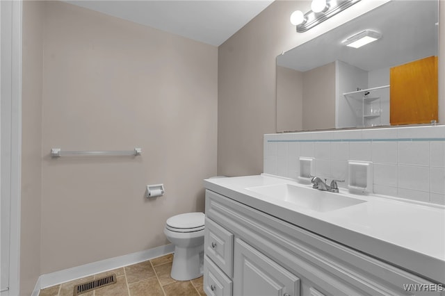 bathroom with vanity, backsplash, toilet, and walk in shower