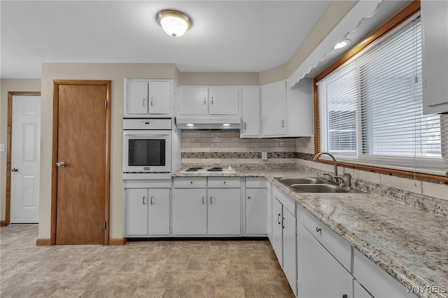 kitchen featuring sink, white appliances, white cabinets, and backsplash