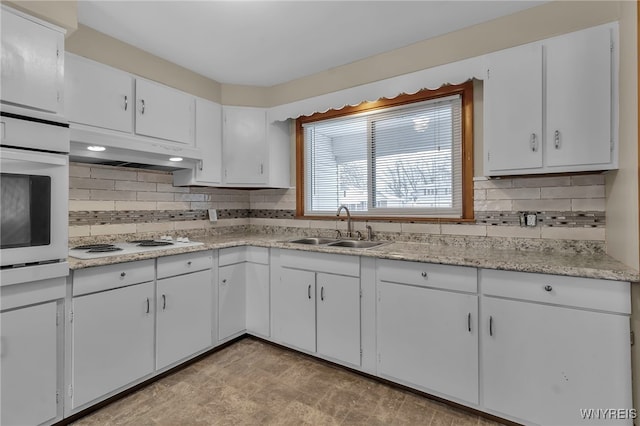 kitchen featuring sink, backsplash, white cabinets, and white appliances