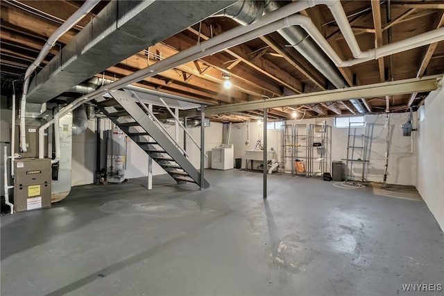 basement featuring gas water heater, sink, heating unit, and washing machine and clothes dryer