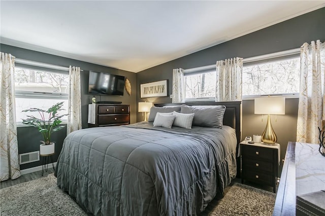 bedroom featuring multiple windows, vaulted ceiling, and hardwood / wood-style flooring