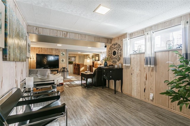 living room featuring wood-type flooring, a textured ceiling, and wooden walls