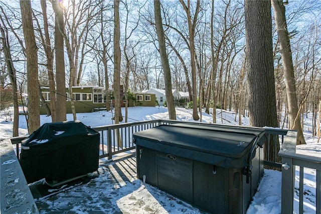 snow covered deck with grilling area and a hot tub