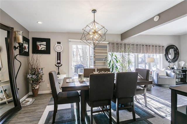 dining area with an inviting chandelier, hardwood / wood-style floors, beam ceiling, and a healthy amount of sunlight