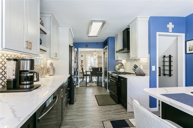 kitchen with stainless steel refrigerator, white cabinetry, light stone countertops, gas range oven, and wall chimney exhaust hood