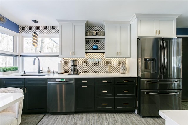 kitchen with decorative light fixtures, sink, white cabinets, backsplash, and stainless steel appliances