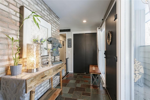 hallway featuring a barn door and brick wall