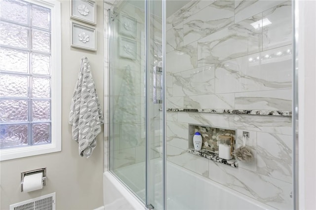 bathroom featuring plenty of natural light and bath / shower combo with glass door