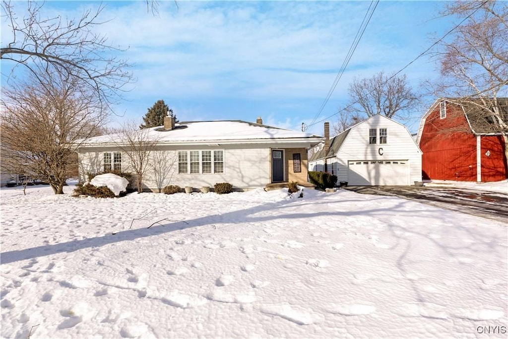 snow covered house featuring a garage and an outdoor structure