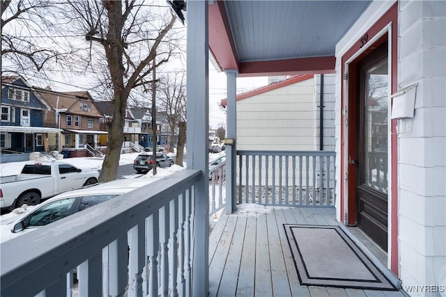 snow covered back of property featuring a porch