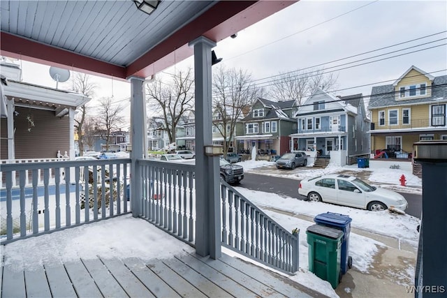 snow covered deck featuring covered porch