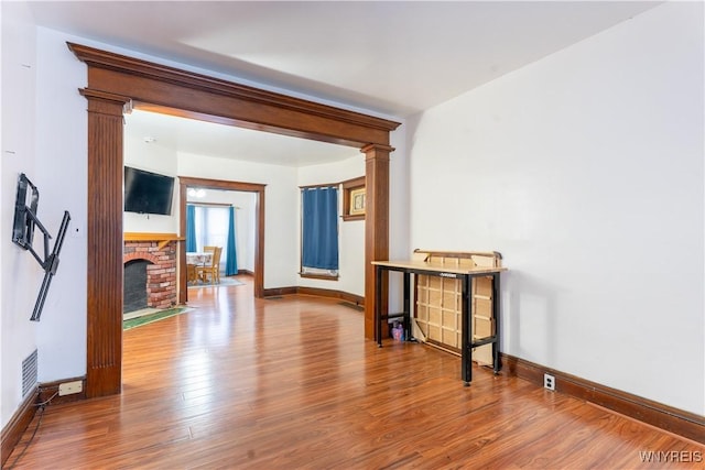 interior space with hardwood / wood-style floors, a fireplace, and decorative columns