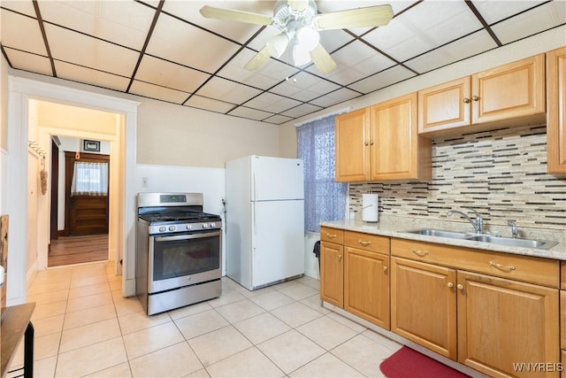 kitchen with decorative backsplash, sink, white fridge, and stainless steel gas range oven