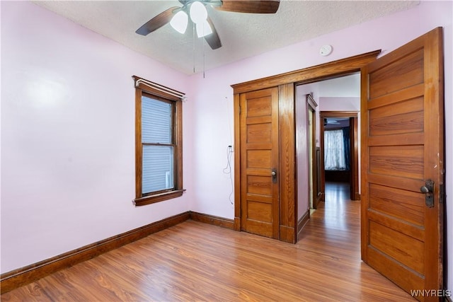 empty room with ceiling fan, light hardwood / wood-style floors, and a textured ceiling