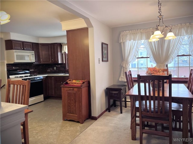 kitchen featuring a wealth of natural light, gas range oven, hanging light fixtures, and backsplash