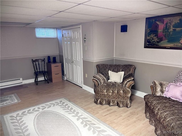 living area with hardwood / wood-style flooring, a baseboard radiator, and a paneled ceiling